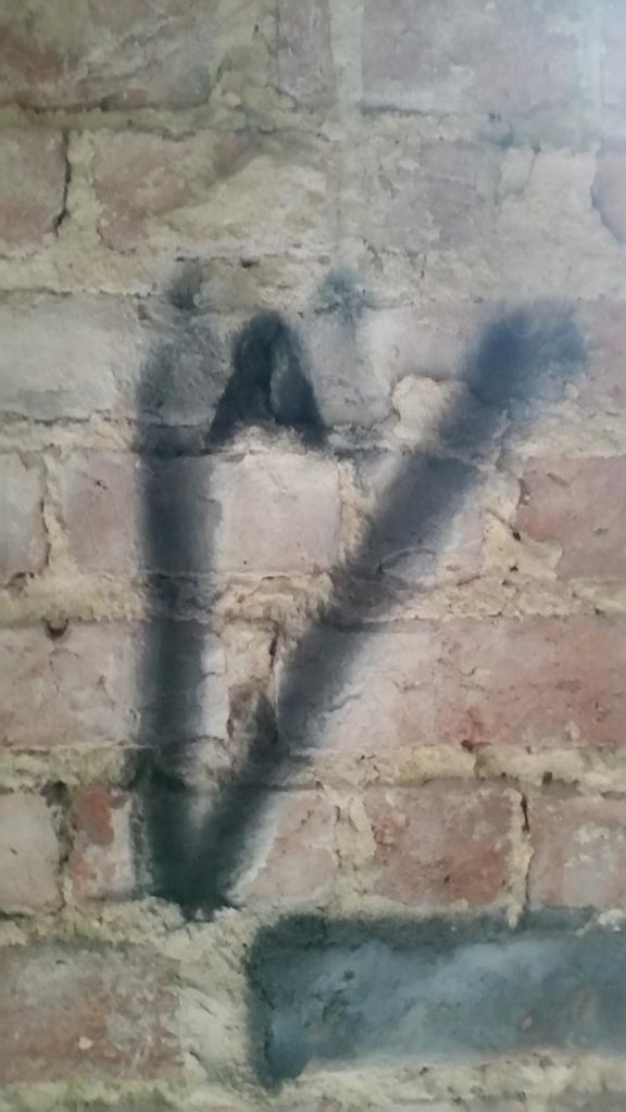 A close-up of the most significant piece of graffiti, thought to be a key to decoding a pigpen cipher embedded on the video itself. 