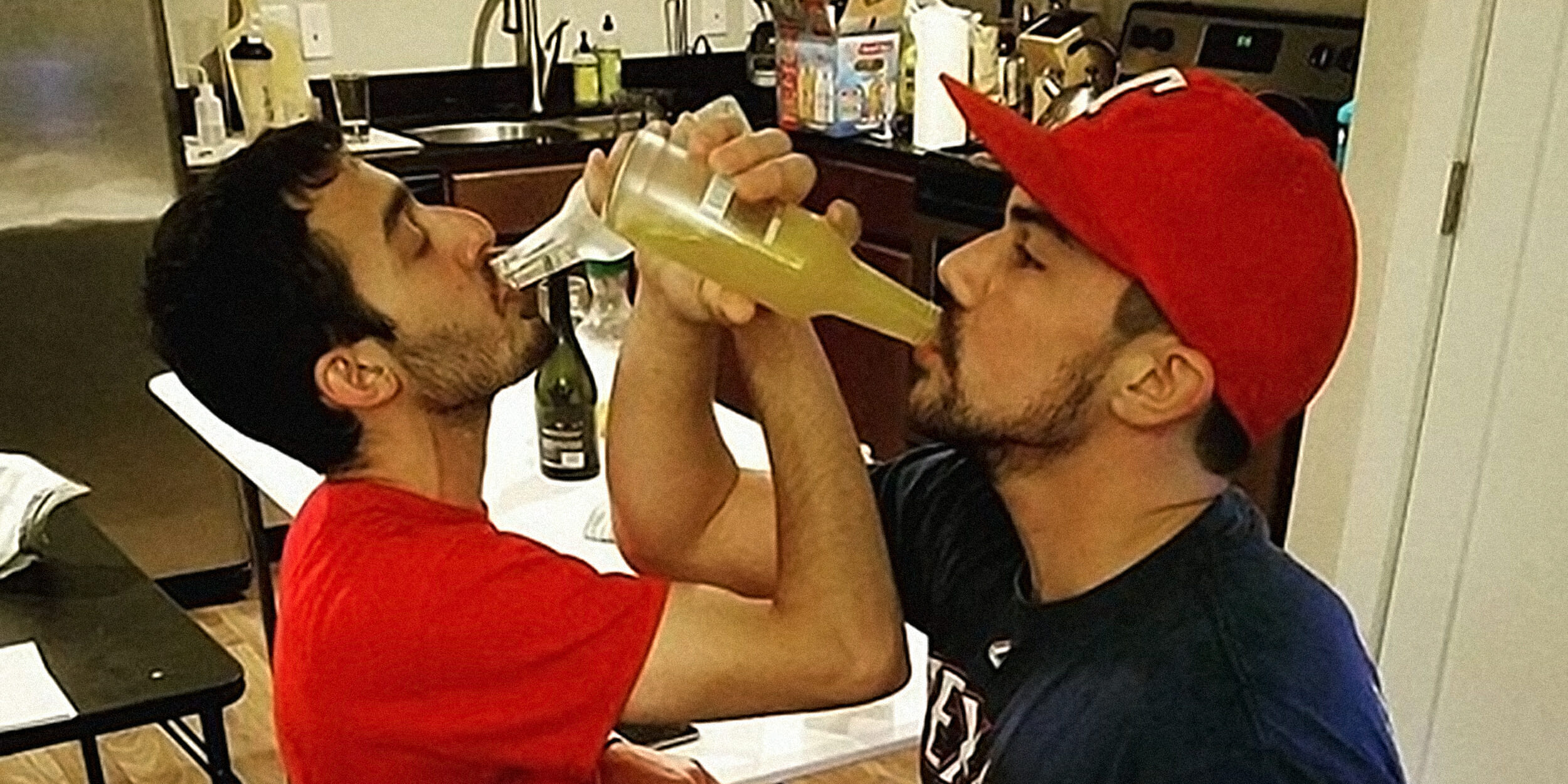 Two men guzzling Smirnoff Ice with arms interlocked bros icing bros