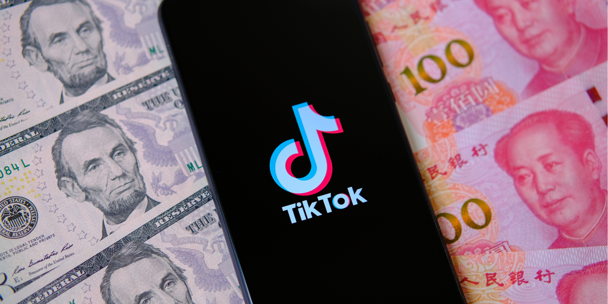 phone with tiktok icon over US and Chinese currency