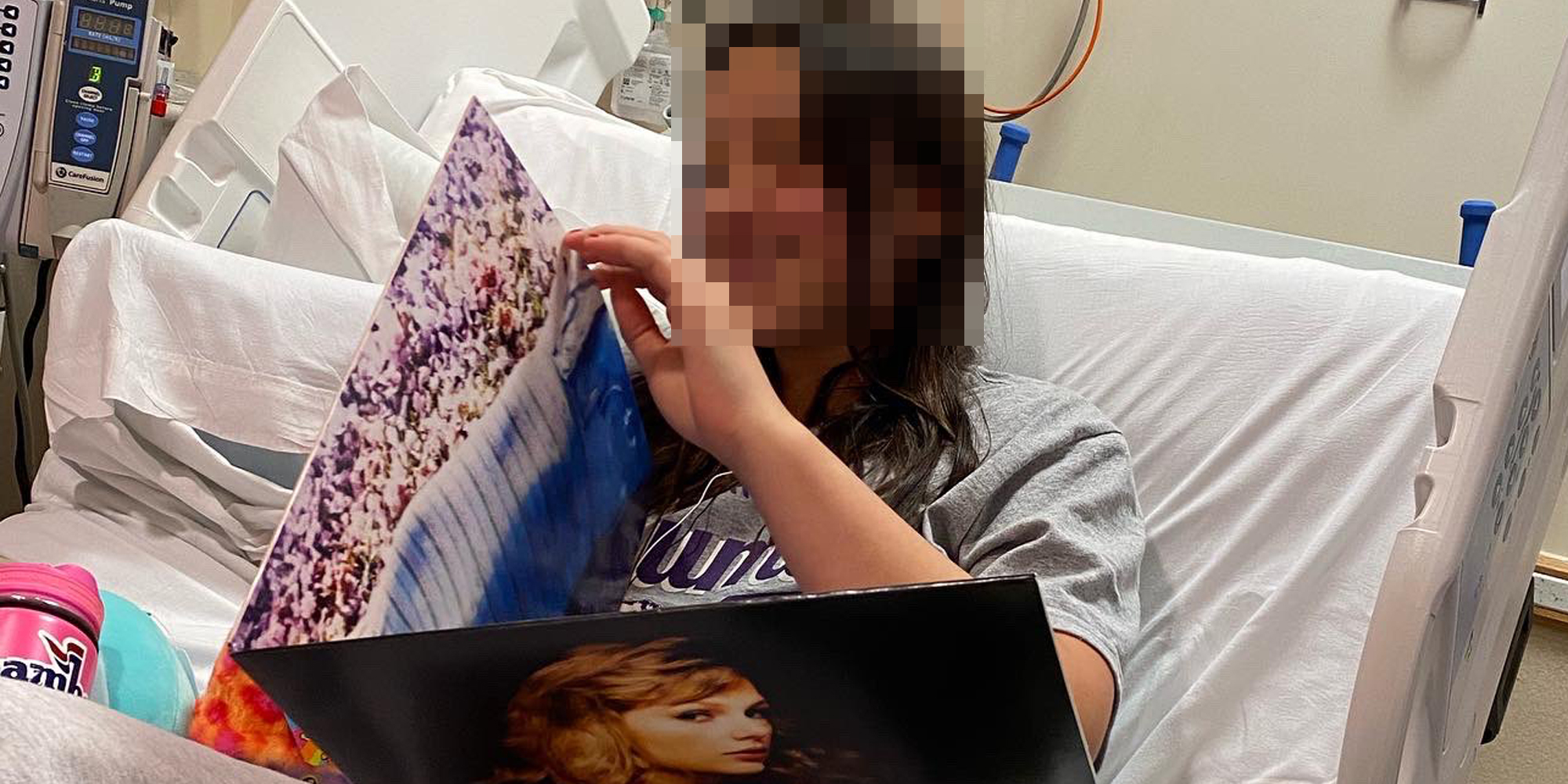 child in hospital bed with face blurred holding Taylor Swift album