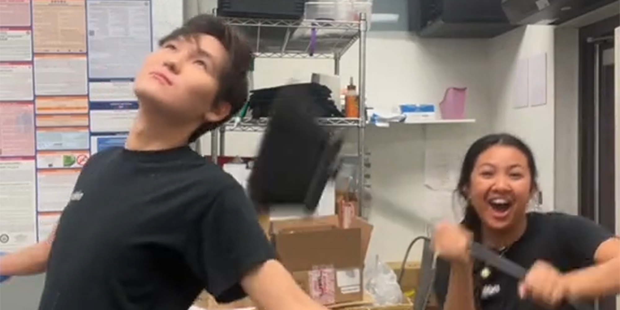 young woman laughing while hitting young man with broom