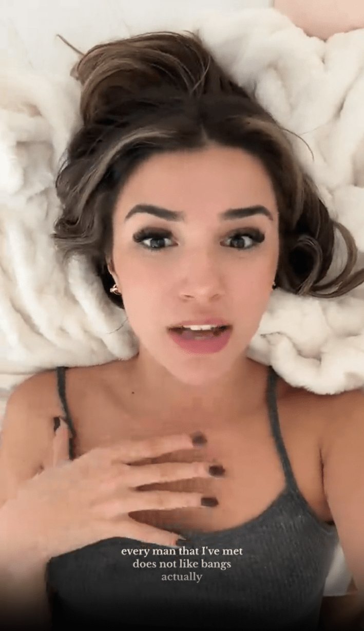 A brunette woman lying on a white fluffy blanket, holding her hand to her chest. Captions on the image read, "every man that I've met does not like bangs actually."