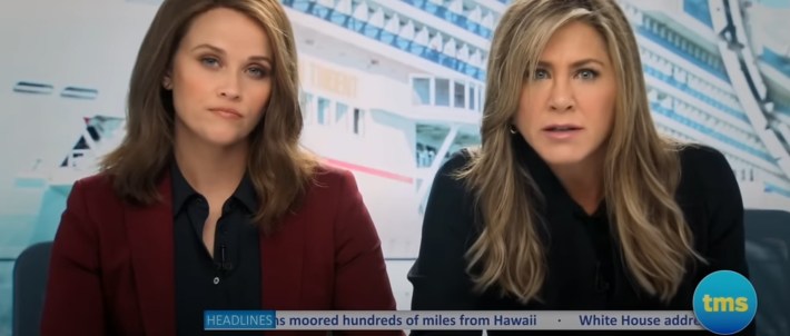 Reese Witherspoon and Jennifer Aniston sitting at a news desk together in a scene from "The Morning Show"