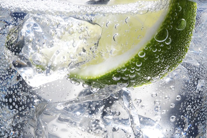 Full glass of fresh cool tonic with lime fruits isolated on white background