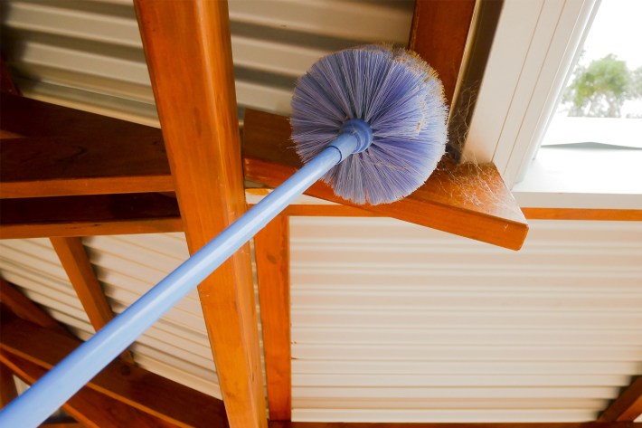 Cobweb brush sweeping spiderweb under the roof