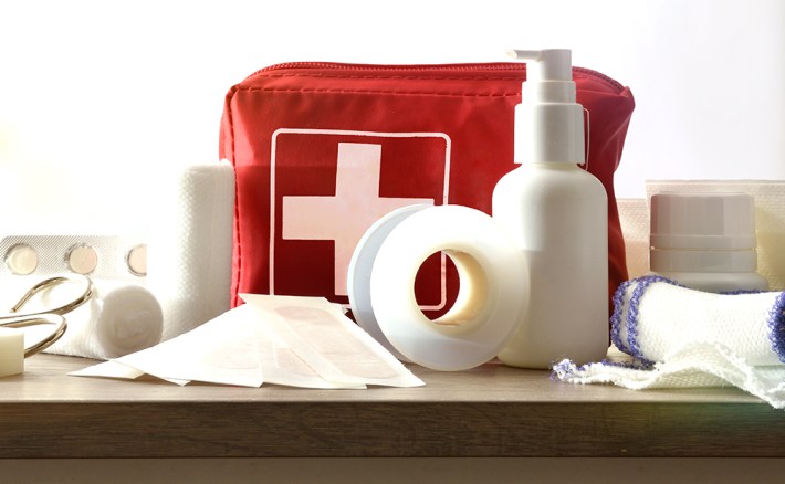 Basic home kit for cures in domestic accidents on a wooden table in a room. Horizontal composition. Front view.