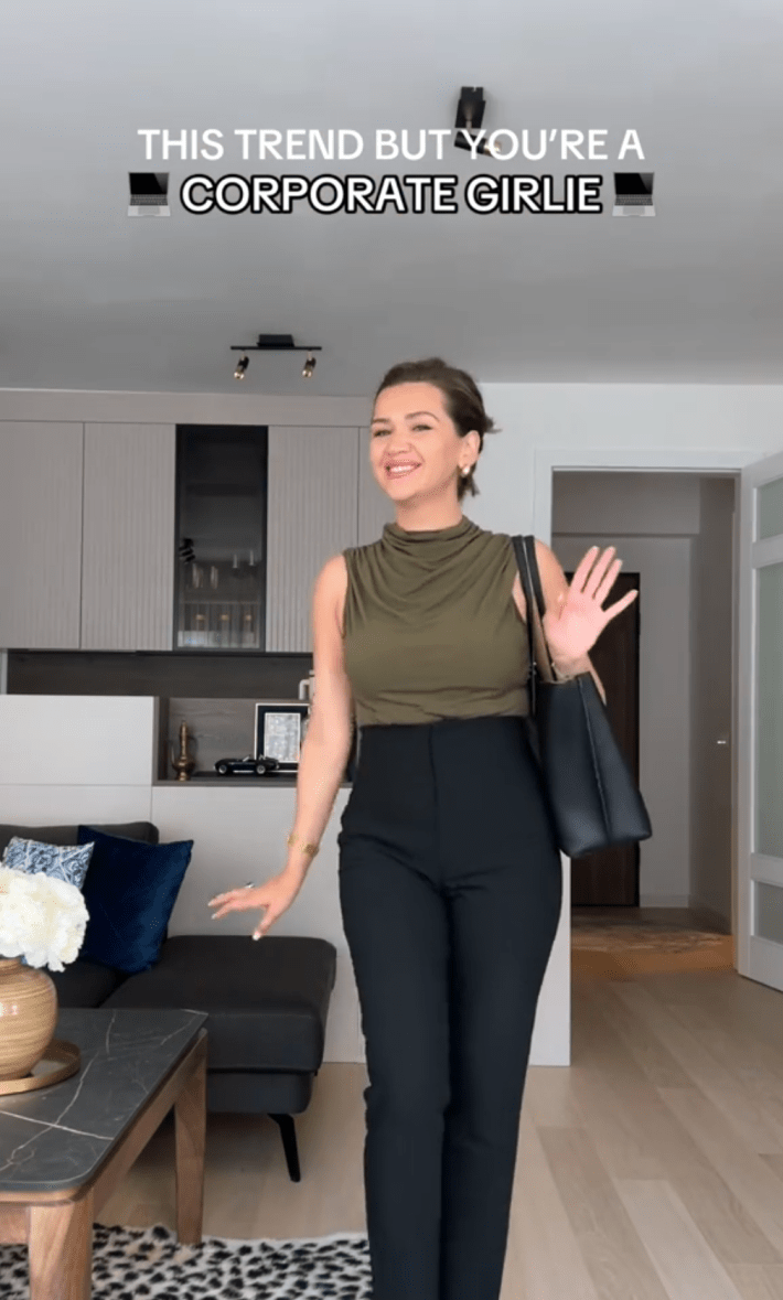 Screenshot of a woman dancing in a corporate outfit smiling for the camera. Text overlay reads, "this trend but you're a corporate girlie" with two laptop emojis.