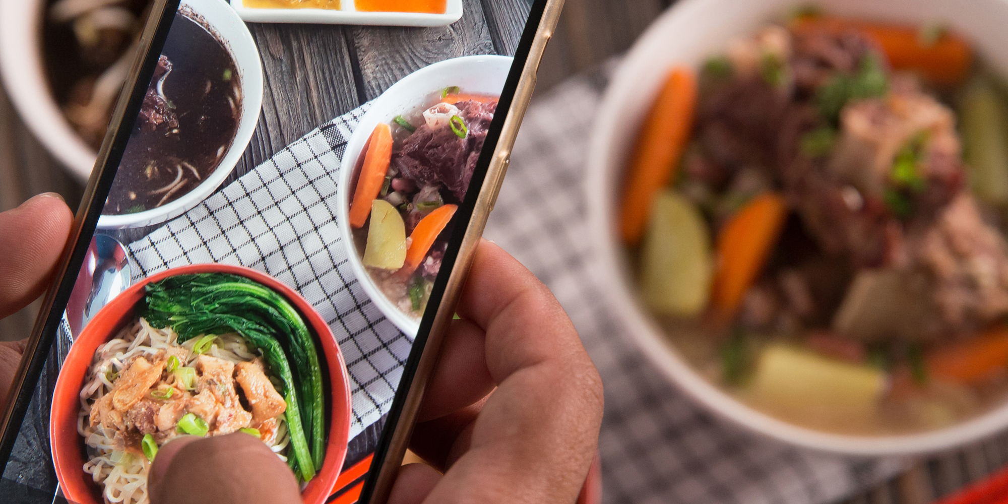 Hand holding phone taking picture of food