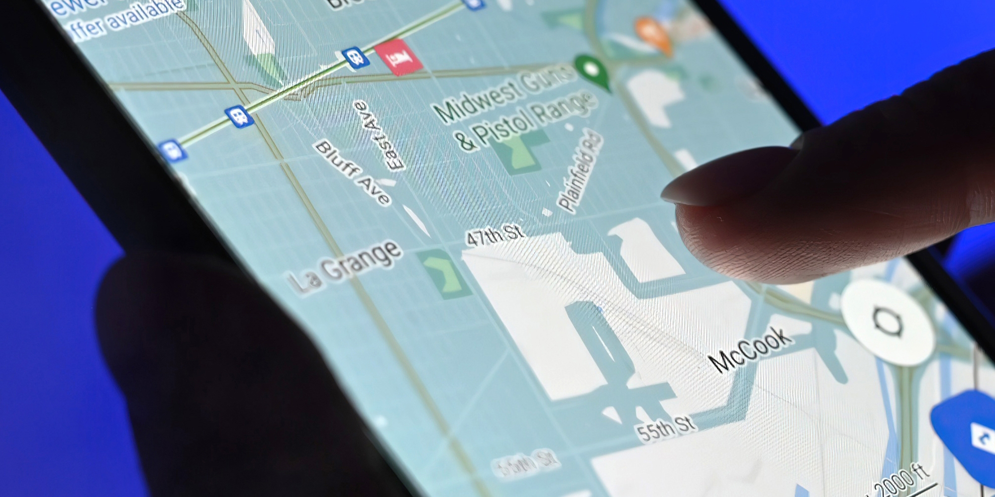 Girl using google maps app on a smartphone against blue background, close up view