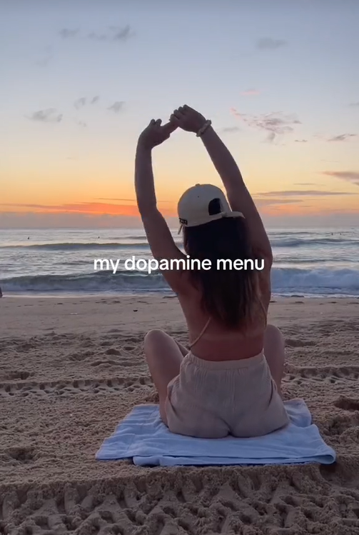 dopamine menu trend with girl sitting on a beach looking at the ocean and stretching