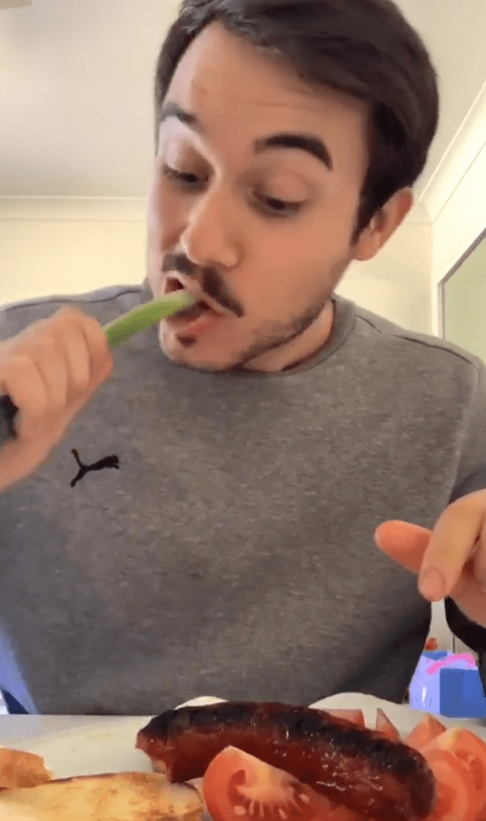 A man eating a Balkan Breakfast biting into a raw spring onion.