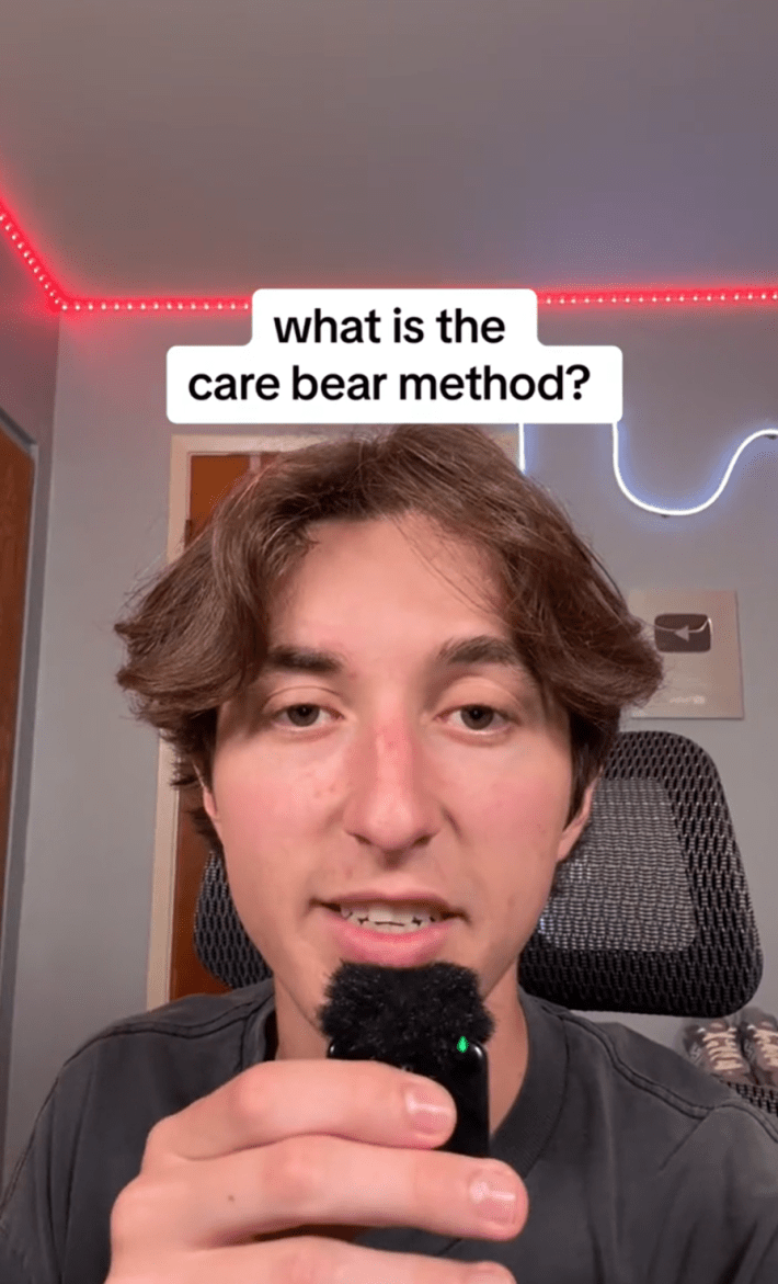 A young man sitting in his desk chair holding a lapel mic in his hand. Text overlay reads, "what ist he care bear method?"