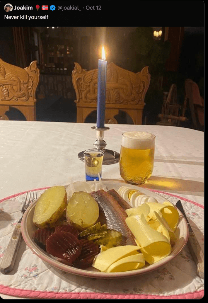 a X post depicting a candellit tabletop. On top of the taletop is a shot of whiskey, a large beer and a large plate of butter, fish, potatoes, pickes and beets (seemingly). The post is captioned "Never Kill Yourself."