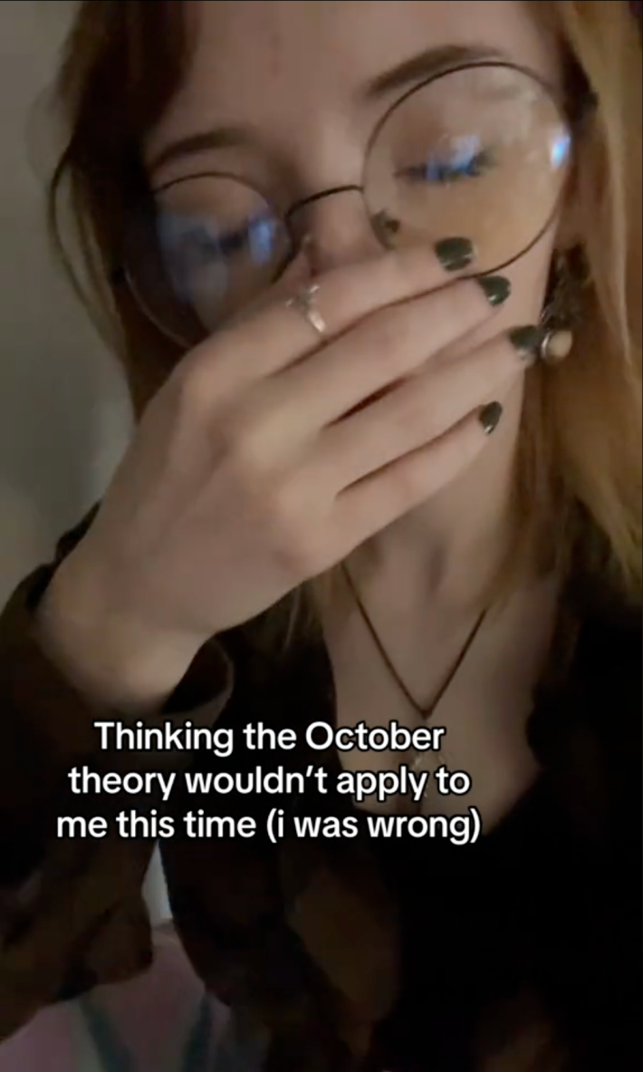TikTok of a woman sighing and rubbing her nose in disbelief. Text overlay reads, "Thinking the October theory wouldn't apply to me this time (i was wrong)"