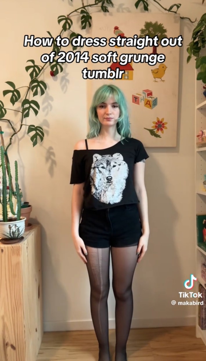 best TikTok aesthetics in 2024: Person with green hair in high-waisted shorts, off-shoulder graphic tee, and tights outfit