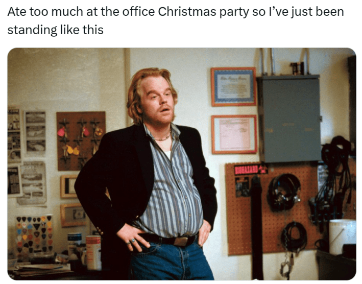 Christmas meme that reads, "Ate too much at the office Christmas party so I’ve just been standing like this" with a photo of a man with a beer belly, his hands on his hips looking very tired.