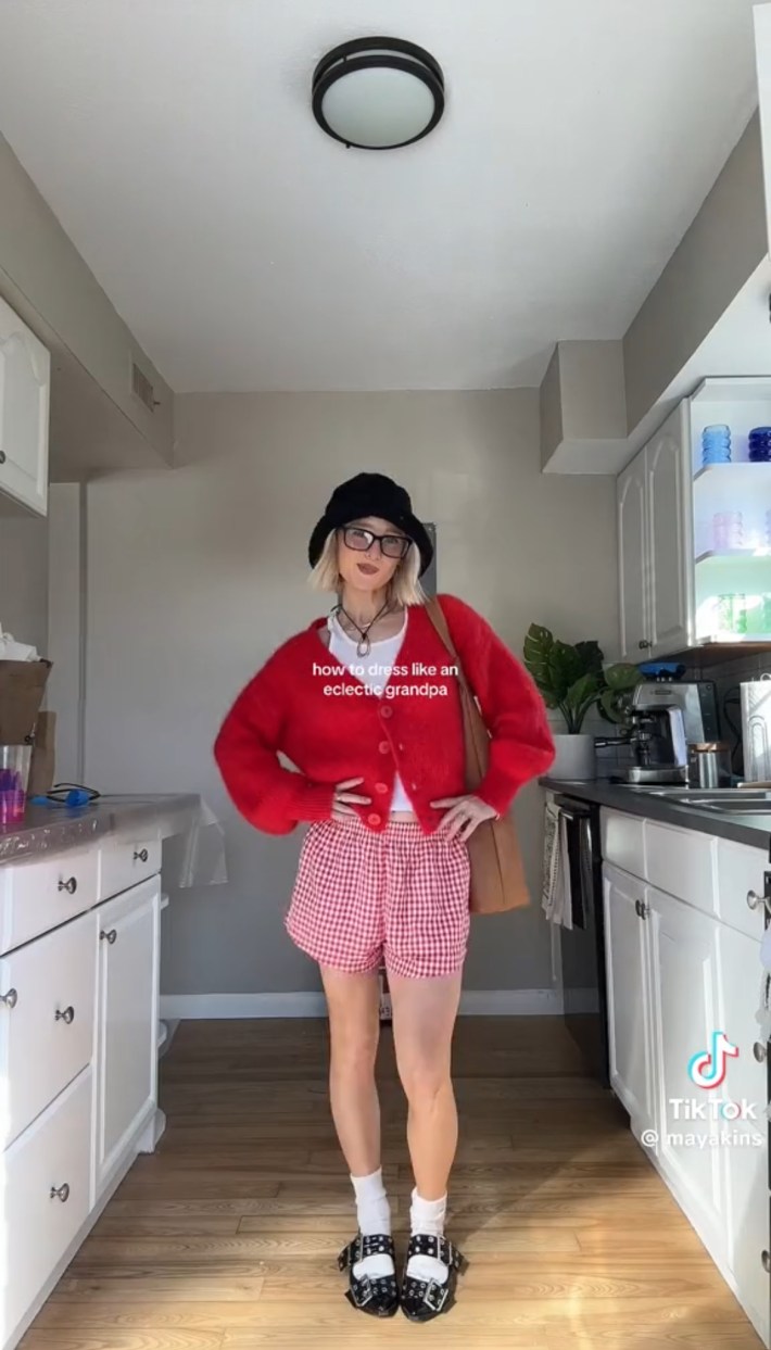best TikTok aesthetics in 2024: Person in black hat, red cardigan, and pinstripe shorts