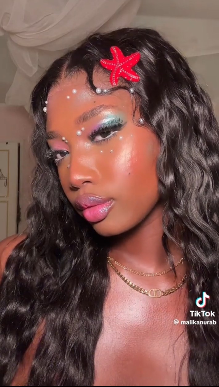 Person wearing purple and green pearlescent eyeshadow and red starfish clip