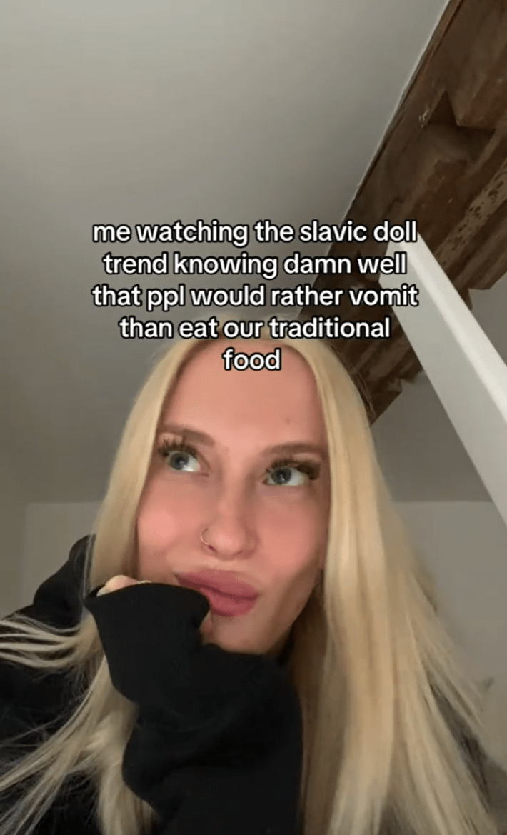 Blonde woman looking off to one side. Text overlay reads, "me watching the slavic doll trend knowing damn well that ppl would rather vomit than eat our traditional food."