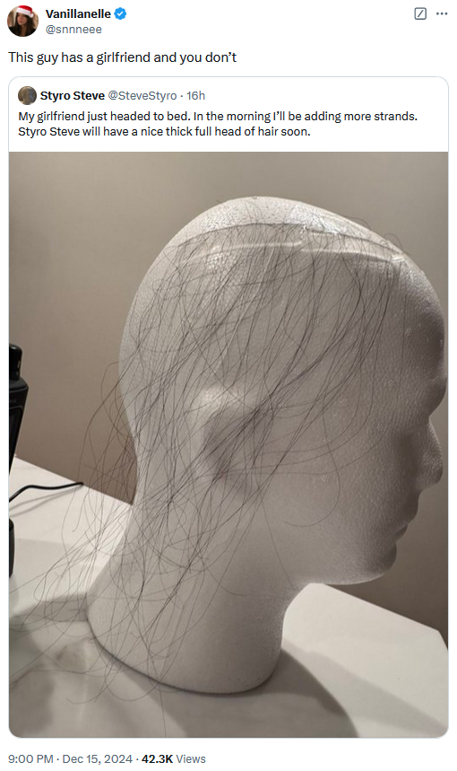 Quote tweet of a post with a Styrofoam head with dark hairs taped to it reading "This guy has a girlfriend and you don't."