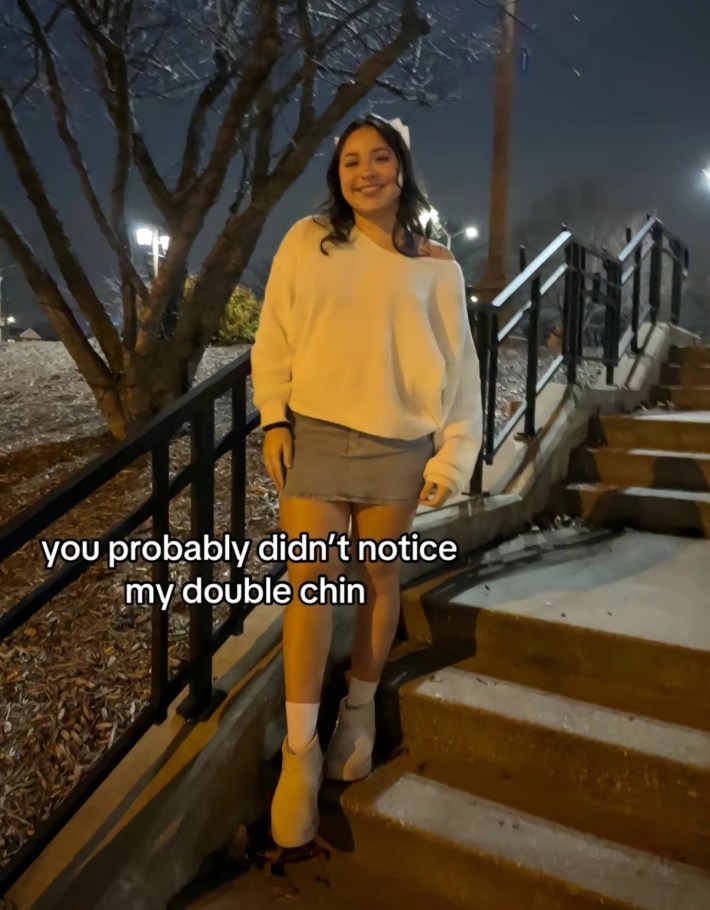 TikTok photo of a young woman smiling for the camera standing on a staircase outside at night. Text overlay reads, "you probably didn't notice my double chin"