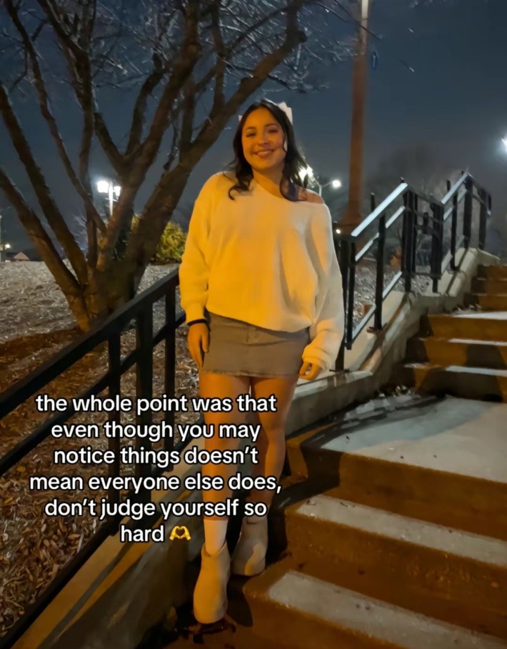 TikTok photo of a young woman smiling for the camera standing on a staircase outside at night. Text overlay reads, "the whole point was that even though you may notice things doesn’t mean everyone else does, don’t judge yourself so hard."