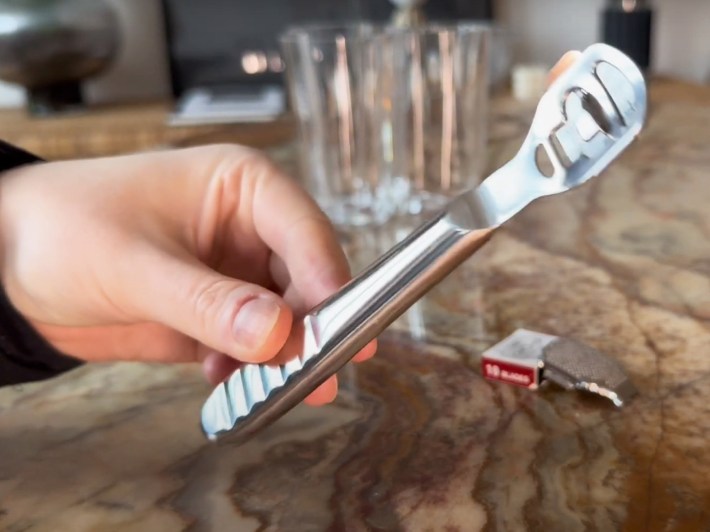 A hand holds a callus remover