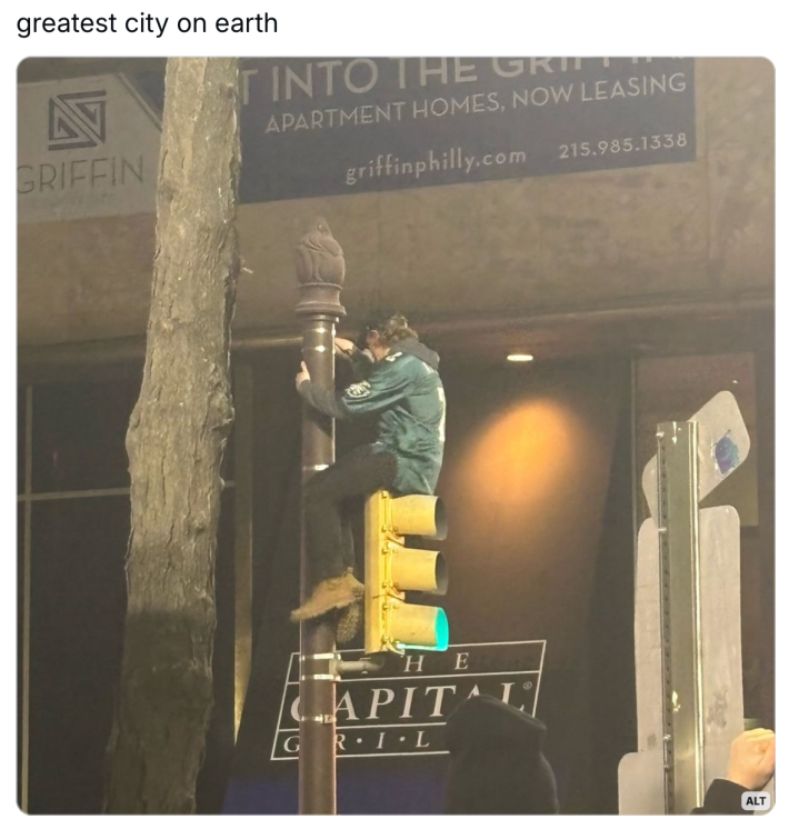 Eagles Super Bowl meme, text reads, "greatest city on earth" with a photo of an Eagles fan sitting on top of a traffic light.