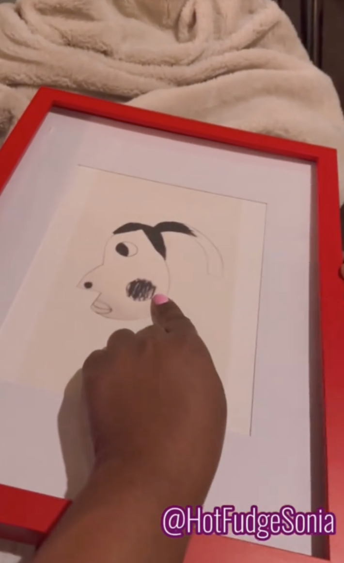 A close up of the TikToker pointing at the hyperpigmentation included in her daughter's portrait of her