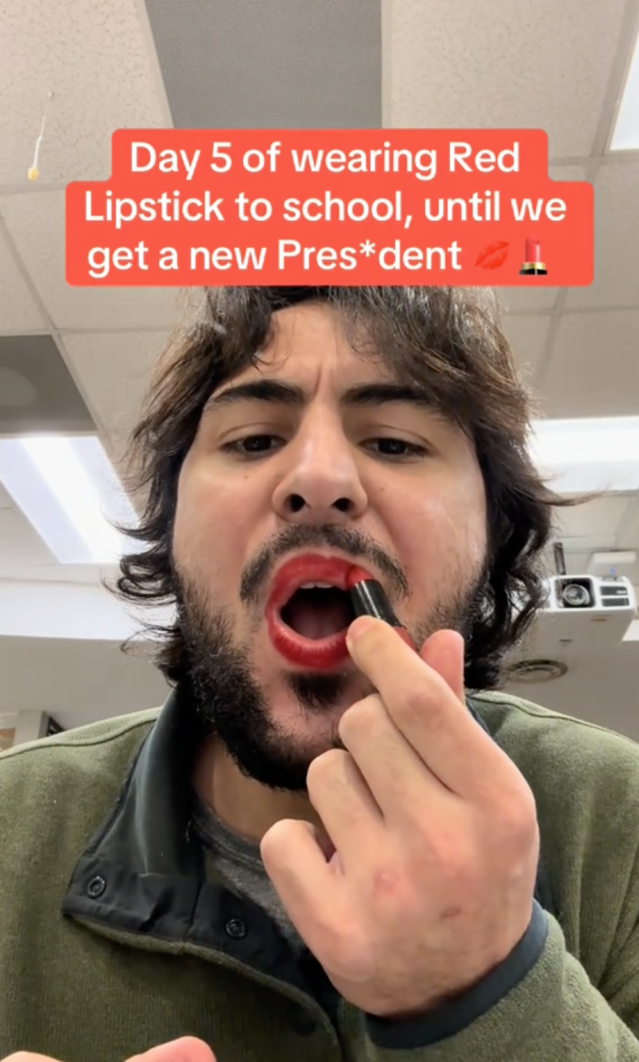 A still of a Tik tok where a masc-looking person is putting on red lipstick