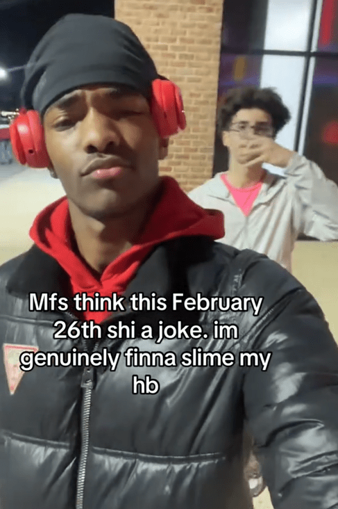TikTok video of a man smirking at the camera with his friend posing behind him and a caption reading "Mfs think this February 26th shi a joke. im genuinely finna slime my hb."