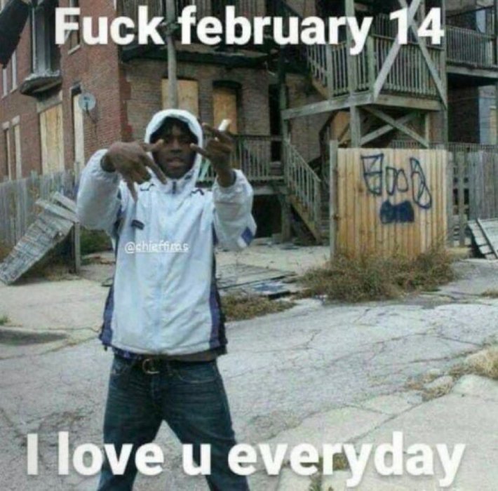 Valentine's Day meme, text reads, "F*ck february 14 I love u everyday" with a guy posing on a run-down street, the wooden fence behind him tagged poorly with the word, "BOOB."