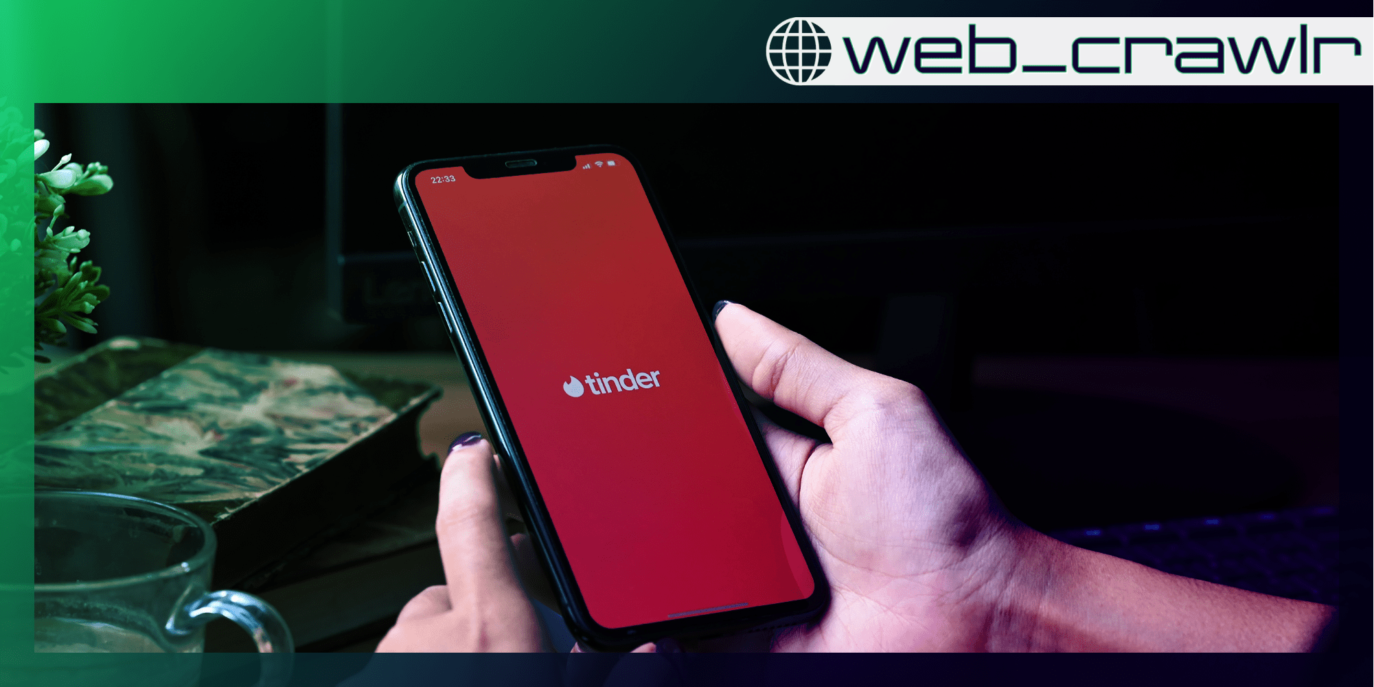 A phone with the Tinder logo on it. The Daily Dot newsletter web_crawlr logo is in the top right corner.