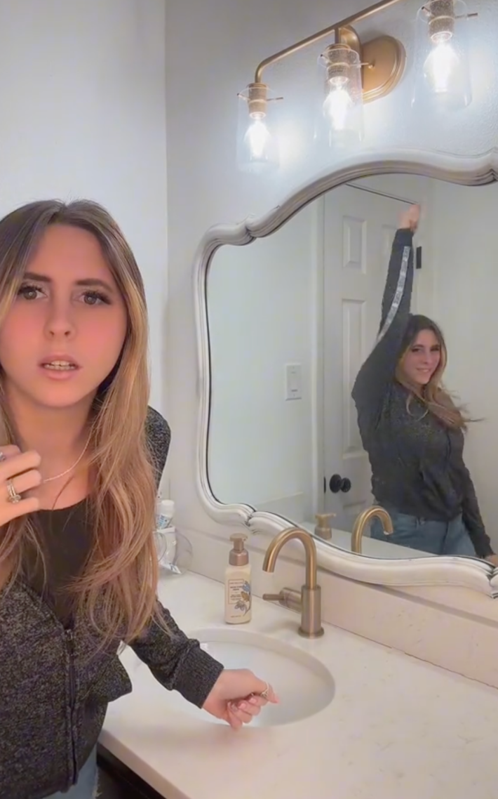 A woman at the end of her anxiety challenge video being creeped out by her reflection in the mirror