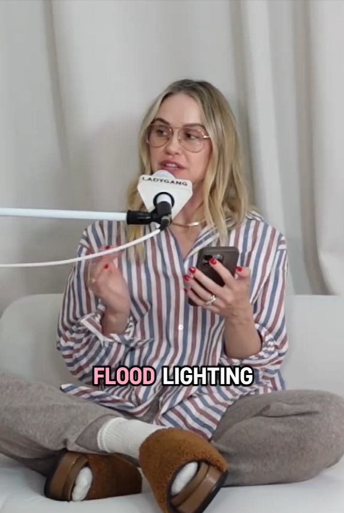 Woman reading a story off of her phone on a podcast. "Flood lighting" is in the text overlay.