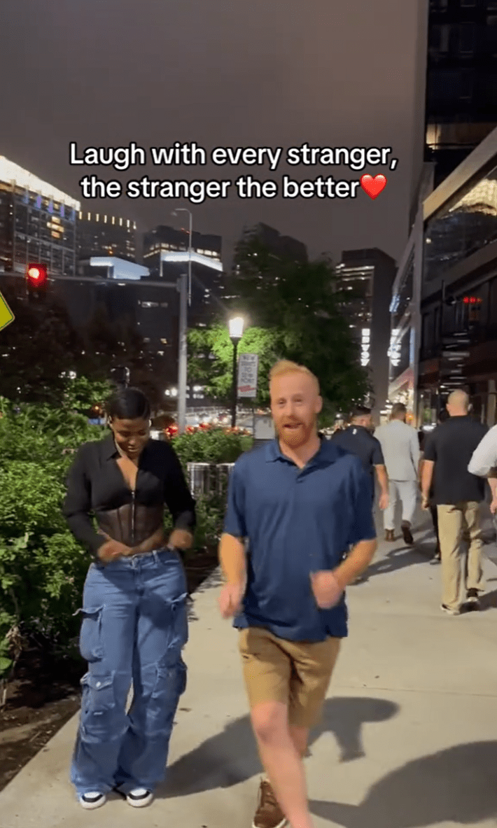 Laugh with every stranger trend, a redheaded man dancing with a Black woman on the street.