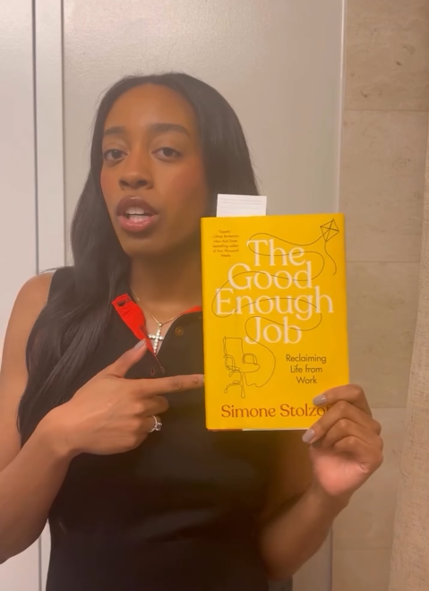 Instagram video of lottery winner @alyssamosley talking to the camera and pointing at the book "The Good Enough Job" by Simone Stolzoff.