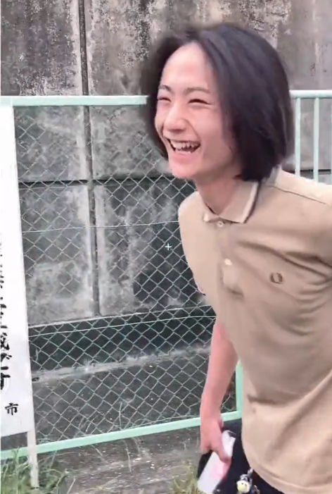TikTok video of a young man laughing outside with a men's bob cut.