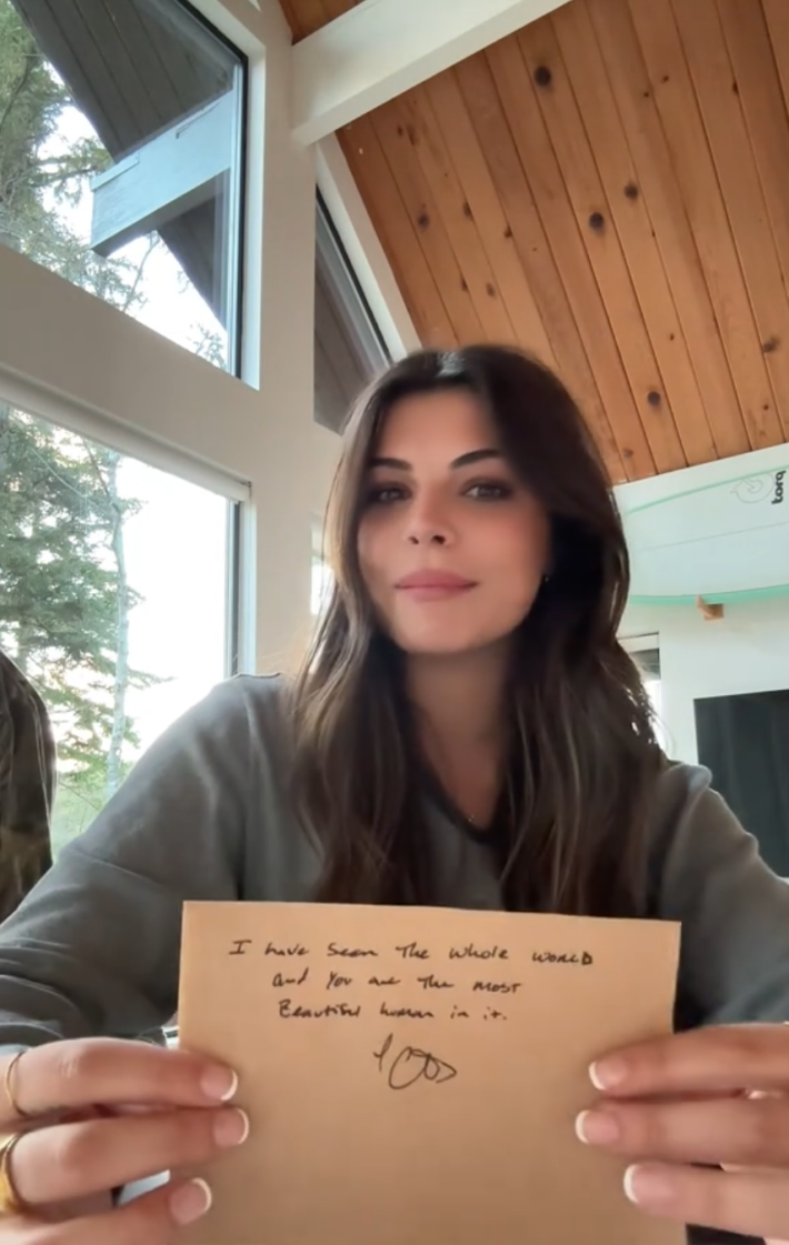 A woman holding up a compliment note from a pilot.