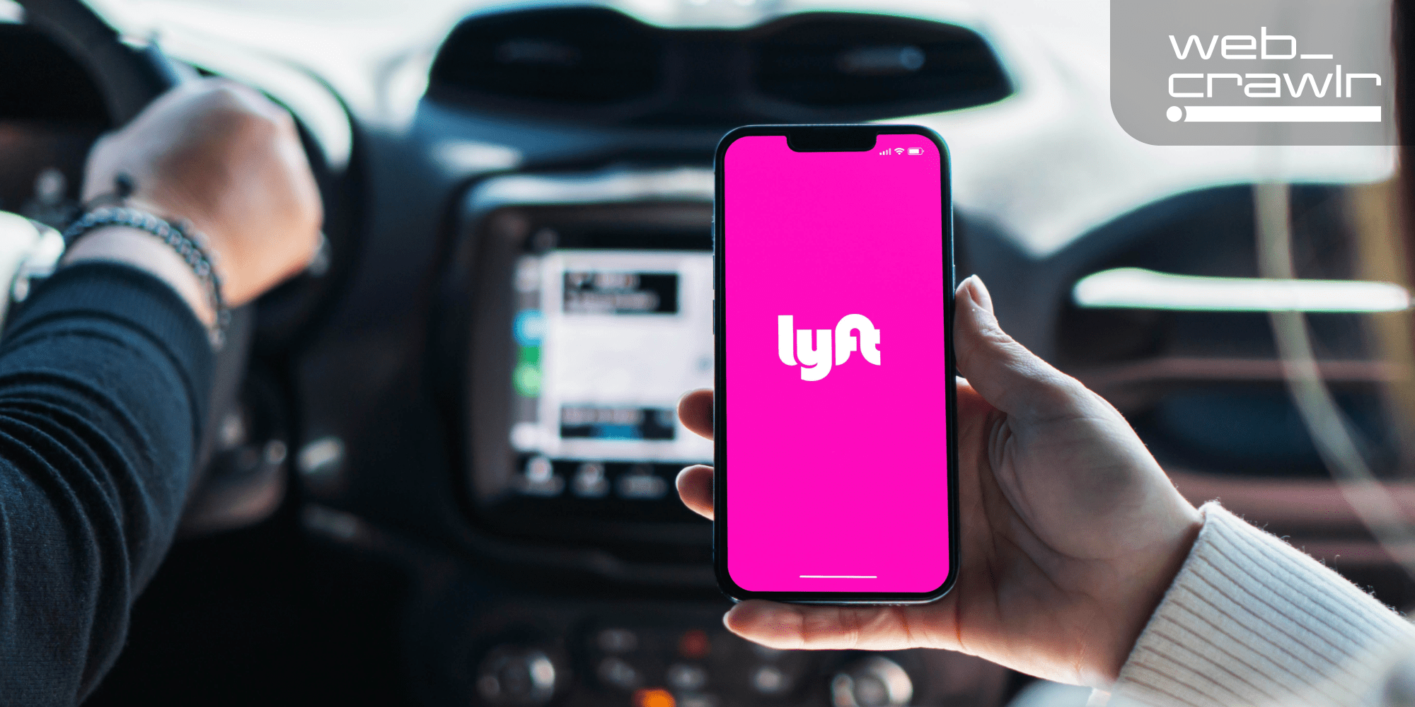 A person holding a phone with the Lyft logo inside a car. The Daily Dot newsletter web_crawlr logo is in the top right corner.