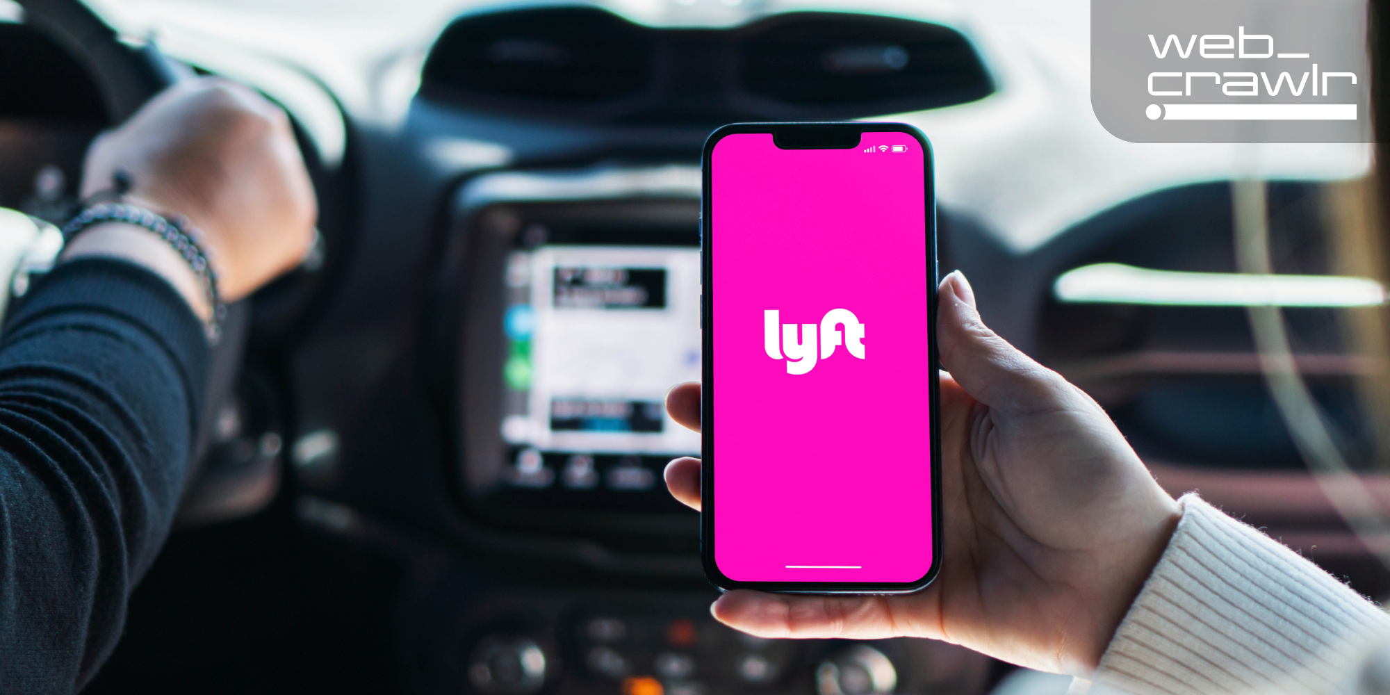 A person holding a phone with the Lyft logo inside a car. The Daily Dot newsletter web_crawlr logo is in the top right corner.