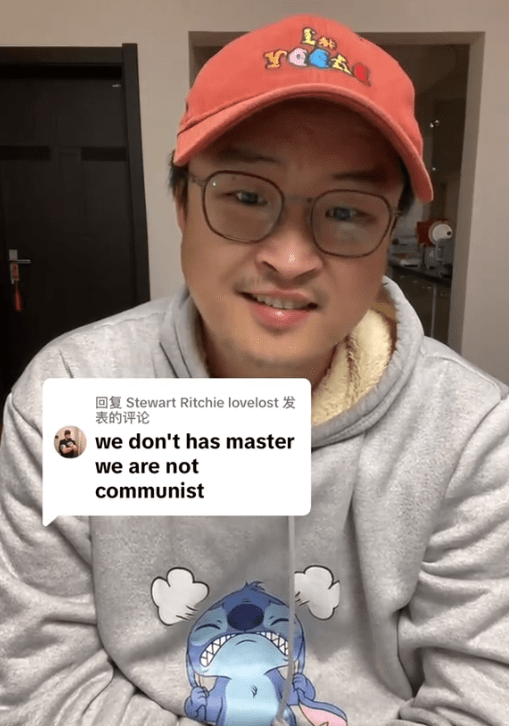 TikTok video of a man smiling at the camera as he replies to a comment reading "we don't has master we are not communist."