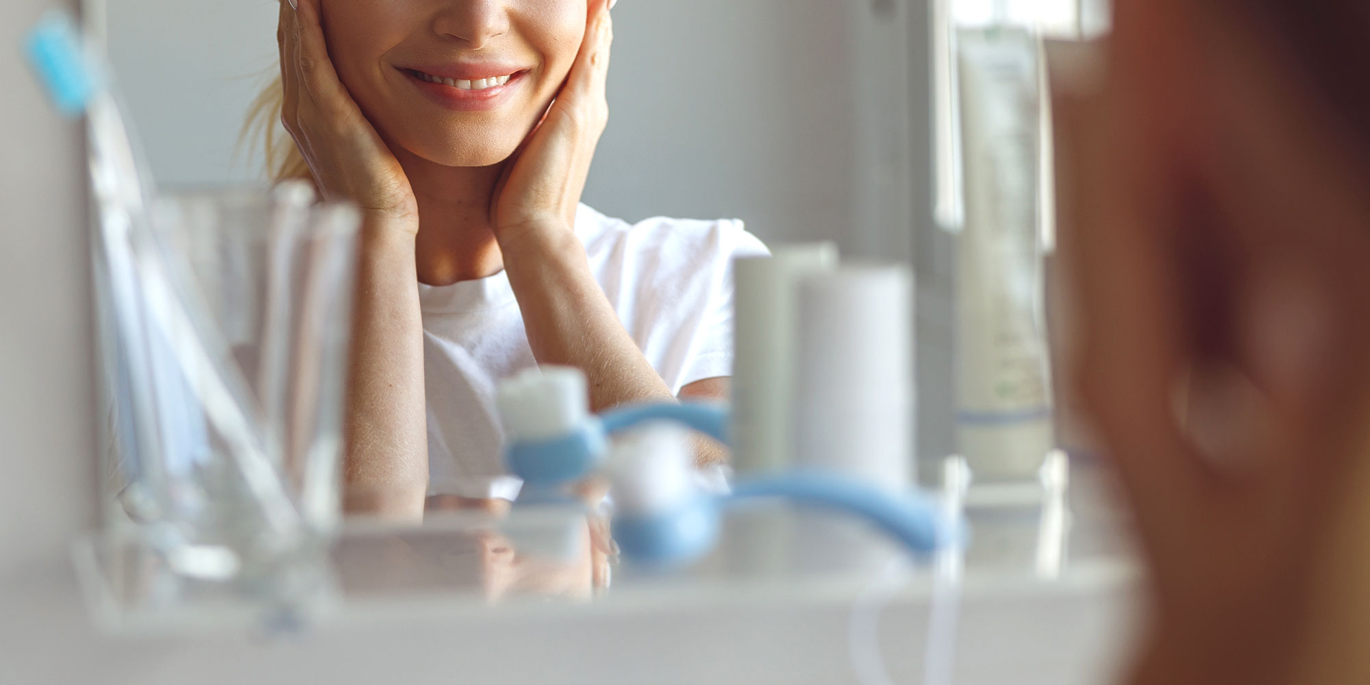 Photo of a woman smiling in a bathroom mirror.