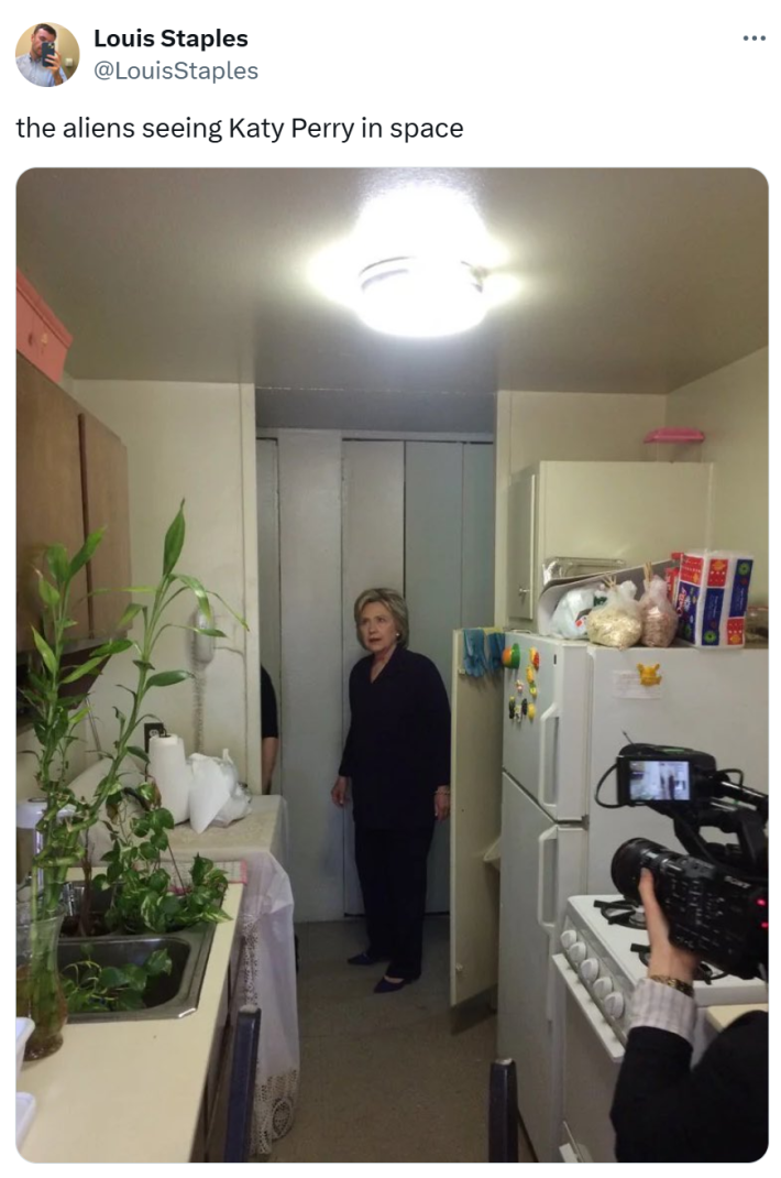 Tweet that reads, "the aliens seeing Katy Perry in space" with meme photo of Hillary Clinton in a small kitchen.