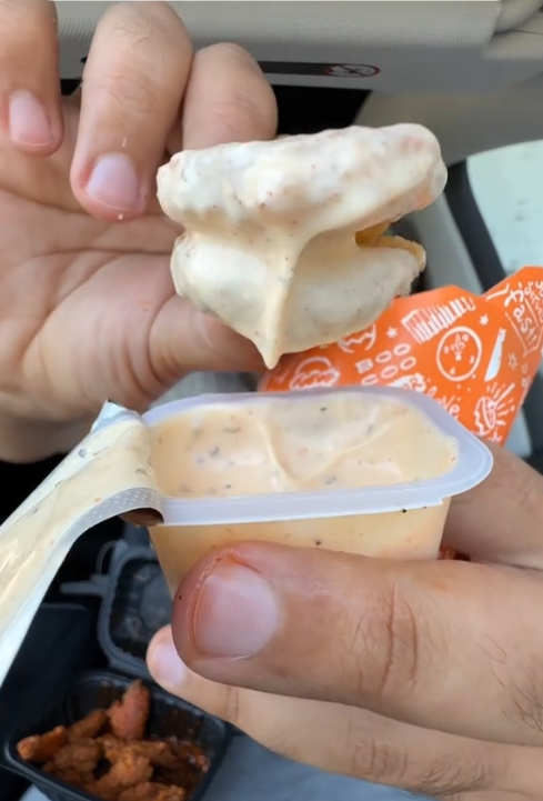 Popeyes pickle menu TikTok review showing a close up of the pickle chips covered in sauce.