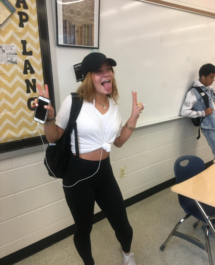A girl posing with two peace signs raised and her tongue sticking out.