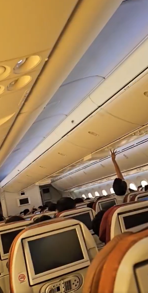 Screenshot of the inside of the airplane, passengers trying to get the air conditioning to work.