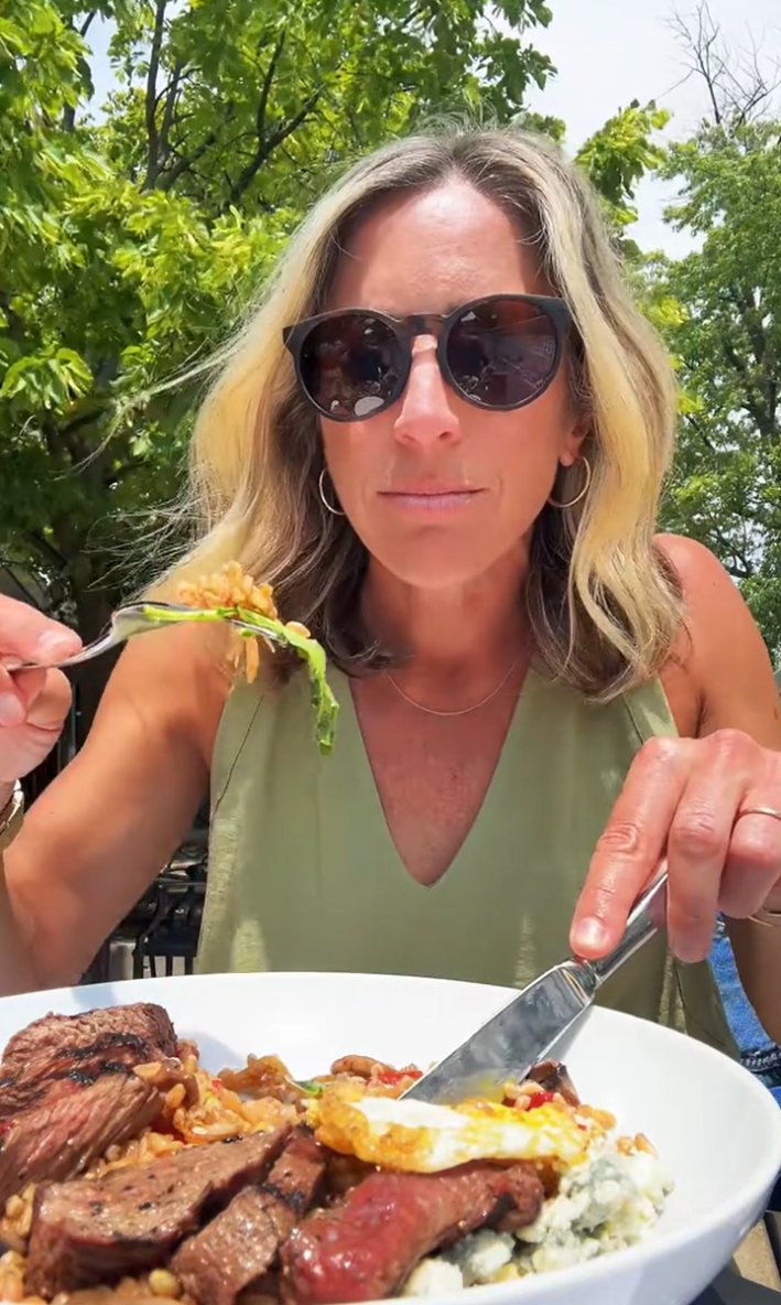 American woman trying to eat food the European way, but her fork is flipped upside down.