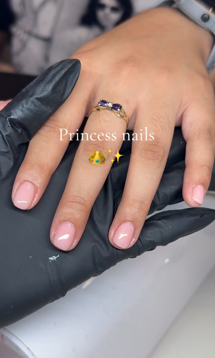 A woman's hand at the nail salon with clean, light pink nails.