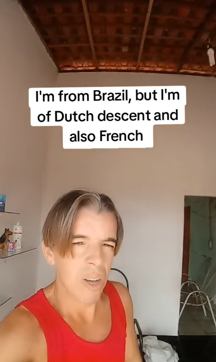 Man who claims to be "36 but looks 17" wearing a red tank top. Text overlay reads, "I'm from Brazil, but I'm of Dutch descent and also French."